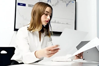 A woman seated at a desk, surrounded by papers and a laptop, representing women's significant role in the global workforce.